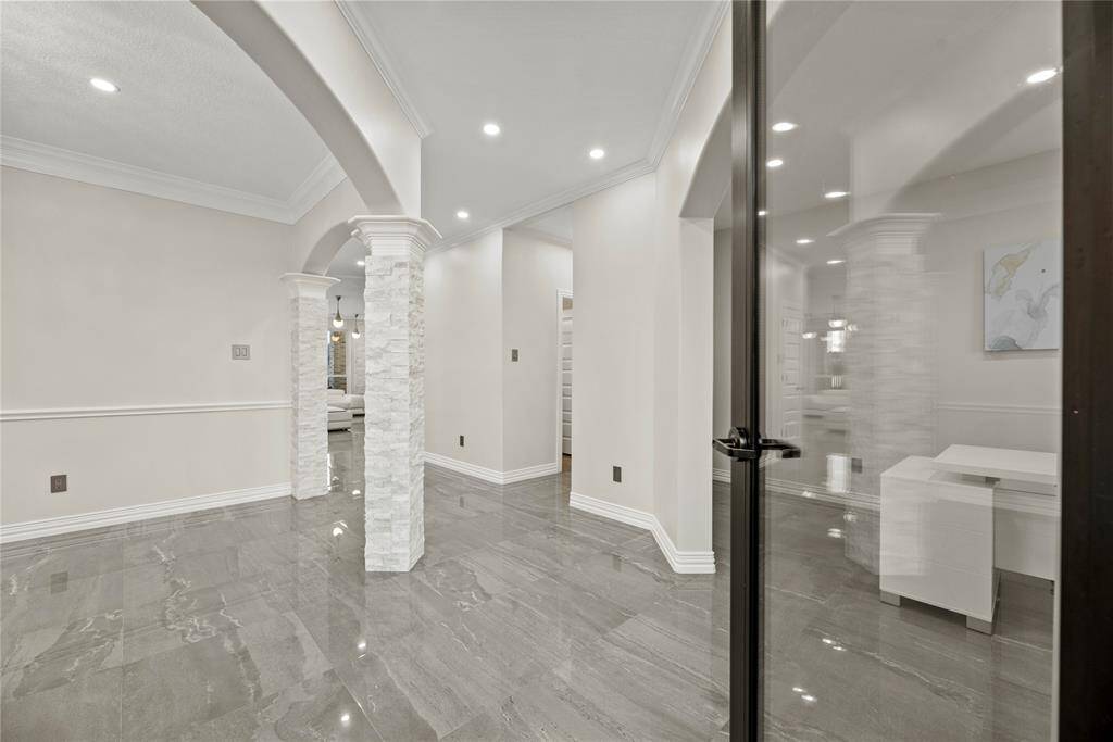 Stunning entrance with elegant stone columns, tile floors, and a modern glass door, seamlessly blending sophistication with a welcoming charm.
