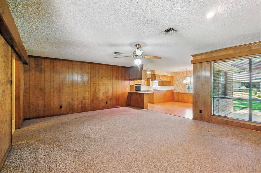 A reverse view of the lavish paneling in the Family Room! The Dining Room and Kitchen are viewed at right center of this picture. The picture windows frame a lovely view of the backyard.