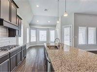 Bright kitchen features ample natural light from large windows, creating an inviting space for cooking and entertaining.