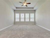 Spacious bedroom with neutral walls and carpeting, featuring a tray ceiling with a