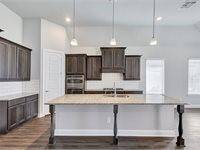 Modern kitchen features dark wood cabinetry, a large central island with