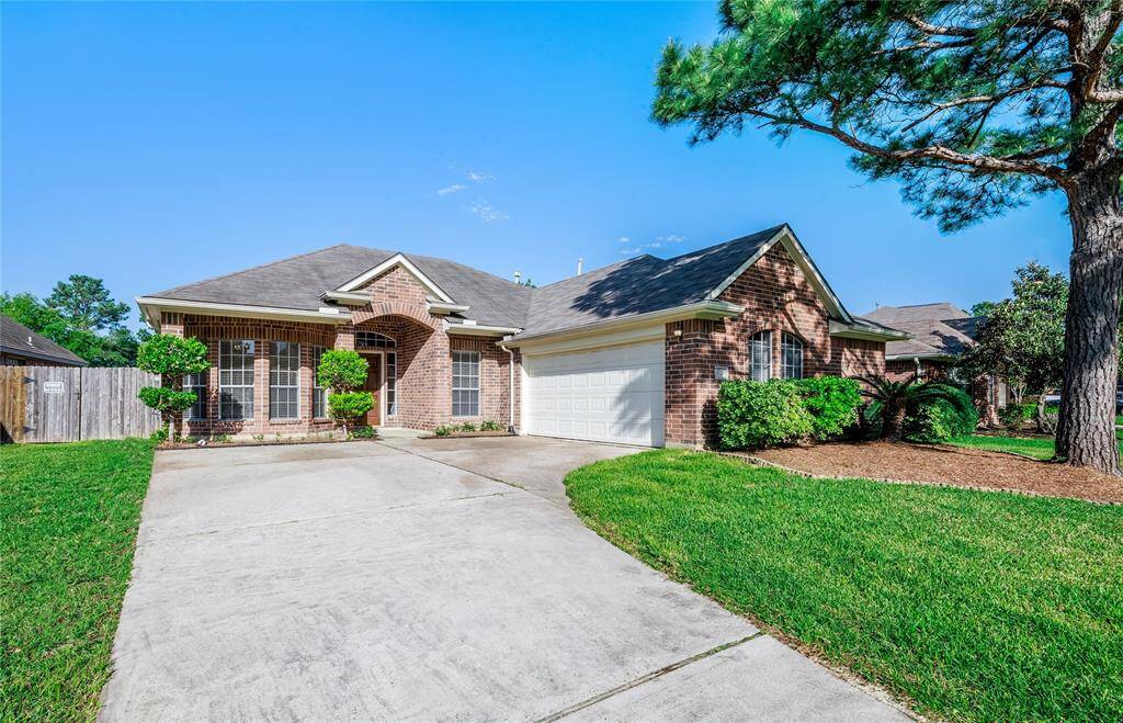 Another angle of the front elevation and attached two-car garage. Big/mature pine tree and professionally landscaped.