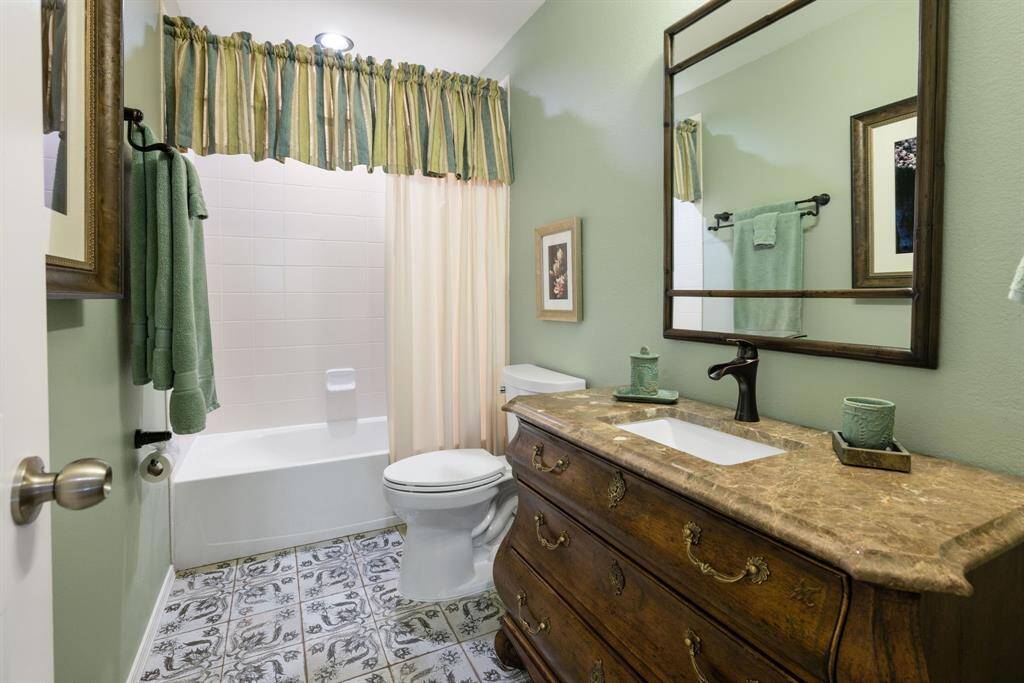 The upstairs bathroom has been thoughtfully updated with a custom piece sink and stylish tile floors. It conveniently serves the third bedroom, providing both functionality and modern elegance.