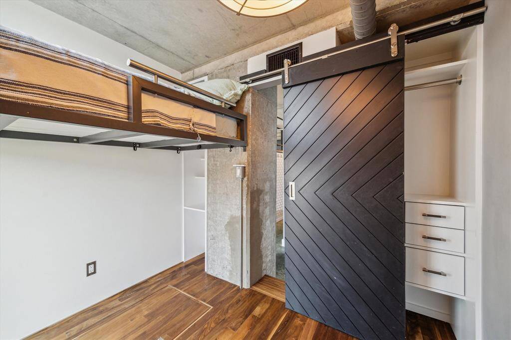 This modern loft features an open living area with high ceilings, exposed brick, and concrete floors. The space includes a cozy seating area, a sleek kitchen with a breakfast bar, and a stylish dining area. A metal staircase leads to an upper level, adding to the industrial charm. Large windows provide ample natural light.