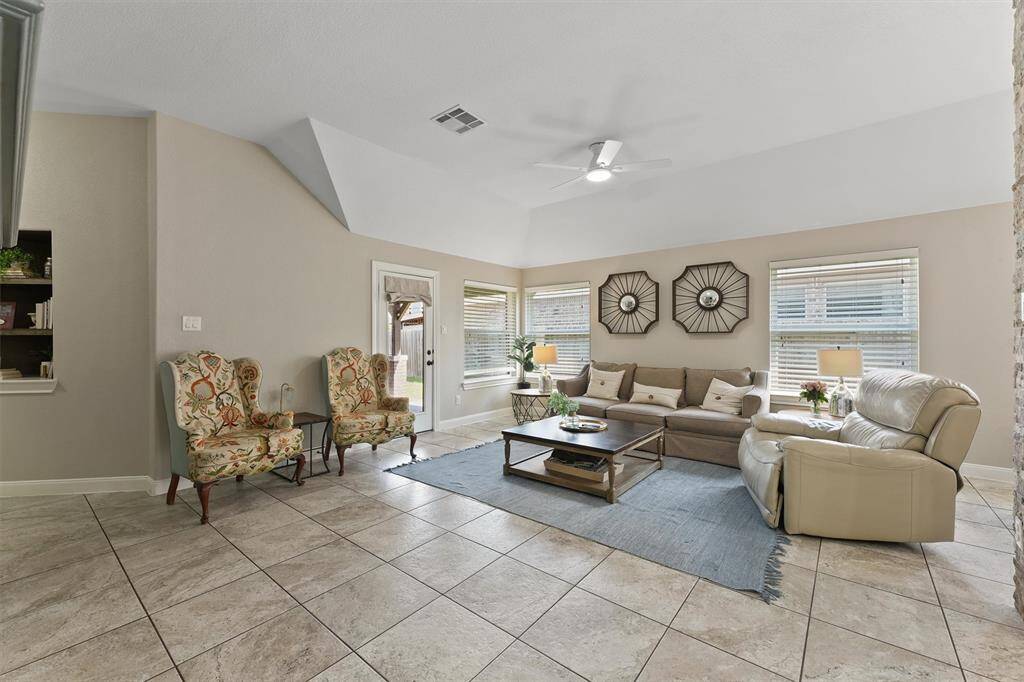 Large windows allow natural light to flood the space, while a glass door leads outside, creating a seamless connection between the indoor and outdoor living areas.