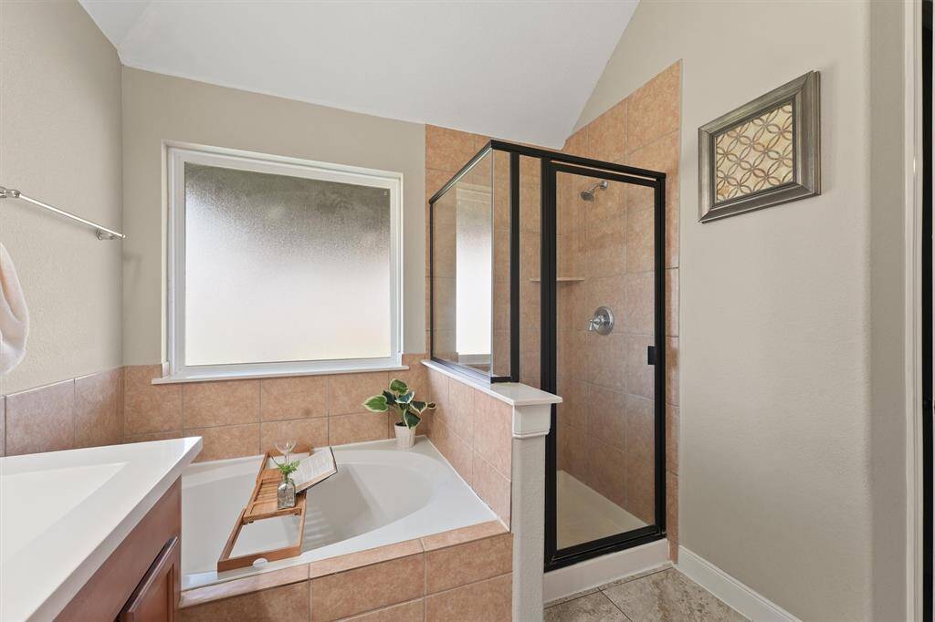 The master bath is a luxurious retreat, featuring a deep soaking tub and a separate glass shower. It's a serene and spa-like atmosphere that makes is perfect for relaxation.