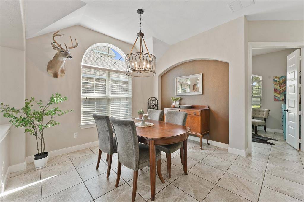 The dining room features an elegant arch accent wall, a stunning custom light fixture, and is bathed in natural light—creating a warm and stylish space perfect for entertaining.