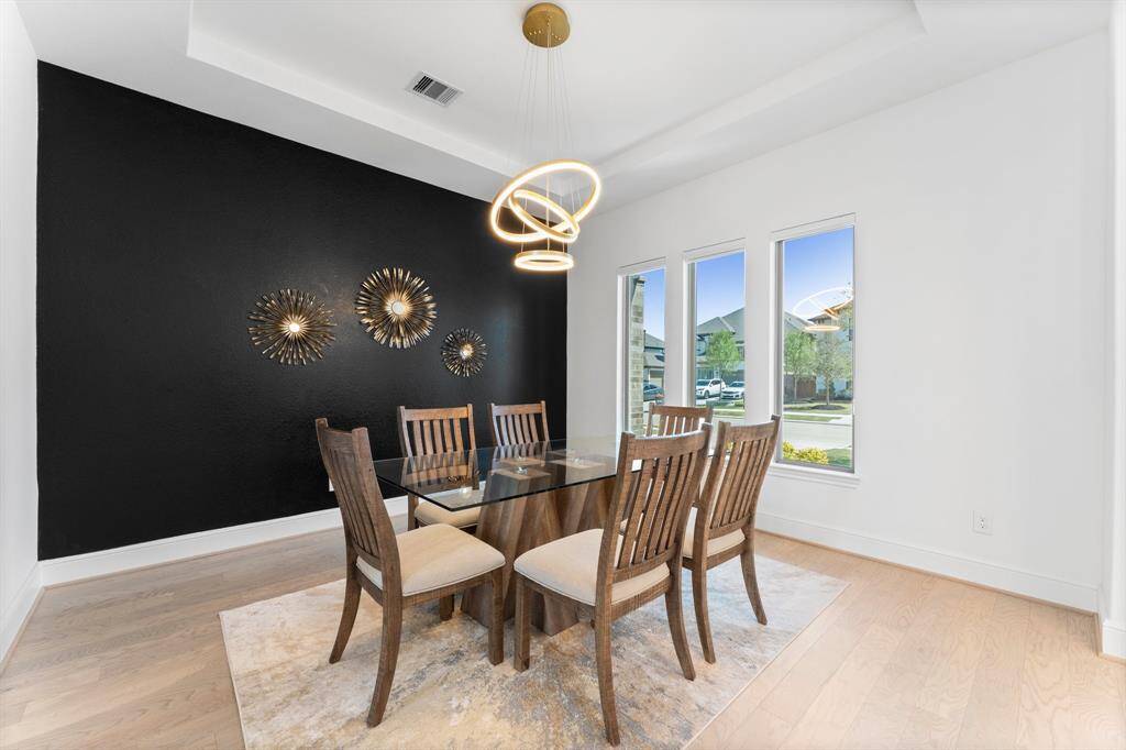The formal dining room features an elegant tray ceiling and a lovely modern gold lighting fixture. The oversized windows provide a lot of natural lighting to this space!