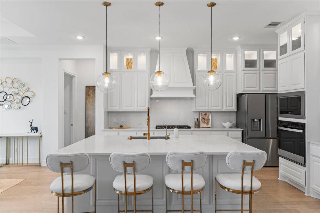 The glass doors on the upper cabinets are so lovely, the various gold accents in the lovely pendent lights and faucets adds elegance!
