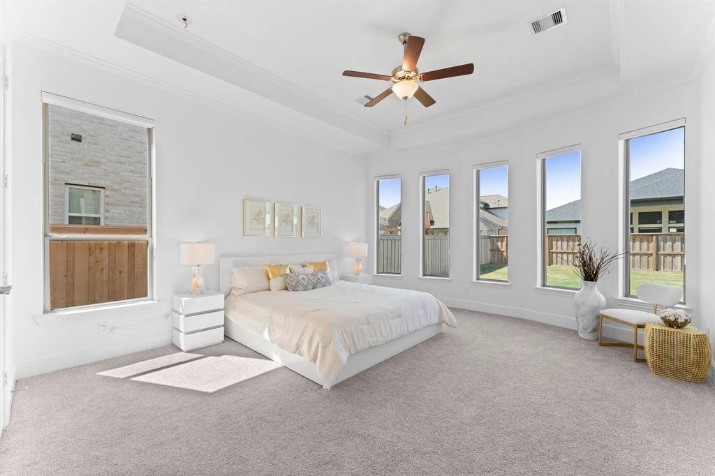 This primary suite features a lovely tray ceiling and 5 oversized windows that let in a lot of natural light - this serene primary suite is pure perfection.