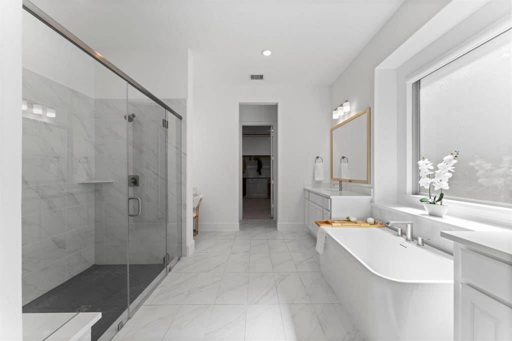 This elegant primary bathroom features an oversized walk-in shower, a beautiful freestanding tub, and a stylish color combination!