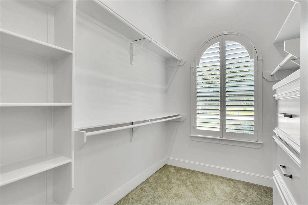 Walk-in closet with shelves and cabinets.