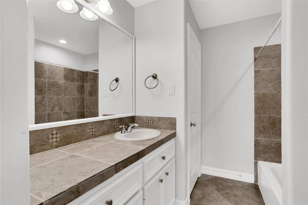 Lovely secondary bathroom complete with recessed lighting, tile floors and plenty of wooden cabinetry.