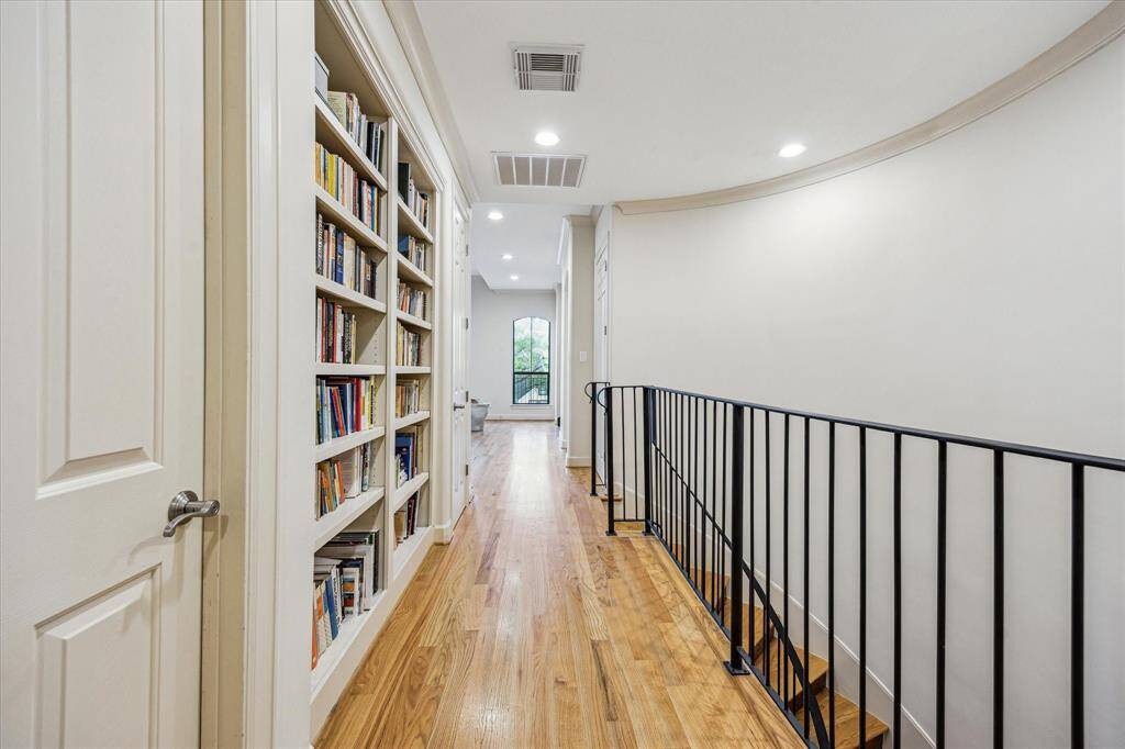 Second floor landing with built in bookshelves showing view of secondary bedroom one and the hall to the playroom/upstairs family room and additional 2 bedrooms.