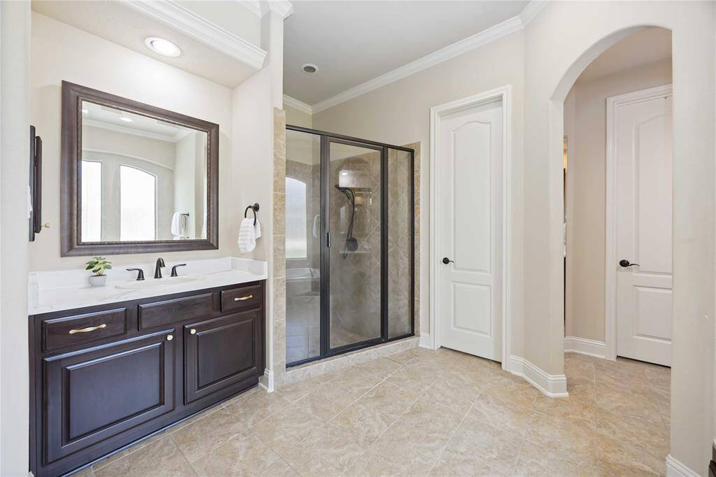 The ensuite bathroom offers a spa-like experience, complete with modern fixtures and his-and-hers sinks for ultimate convenience.