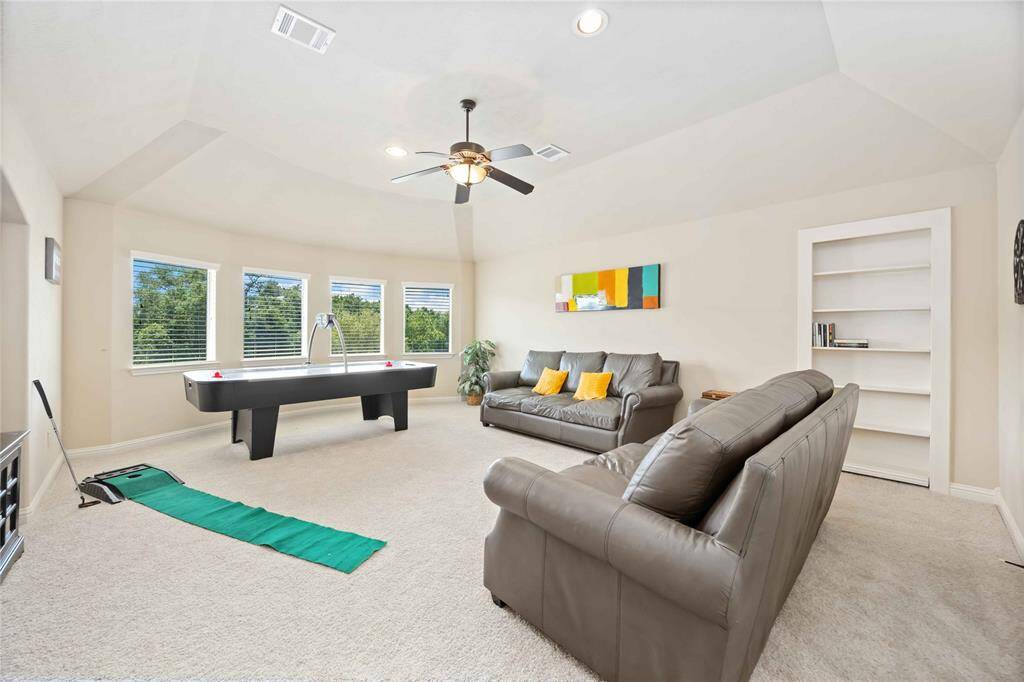 Spacious game room featuring expansive windows and a concealed storage area ample enough to accommodate a bed.