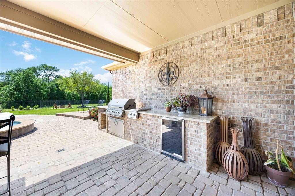 Patio featuring an outdoor kitchen equipped with a grill, beverage refrigerator, and gas stove.