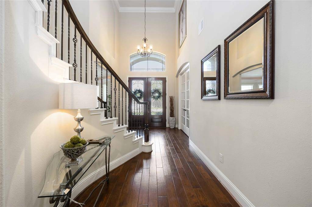 Entrance door, spacious foyer with soaring ceilings and ample natural light, front stairway leading to the upstairs game room and bedrooms, extended hallway leading to the family room.