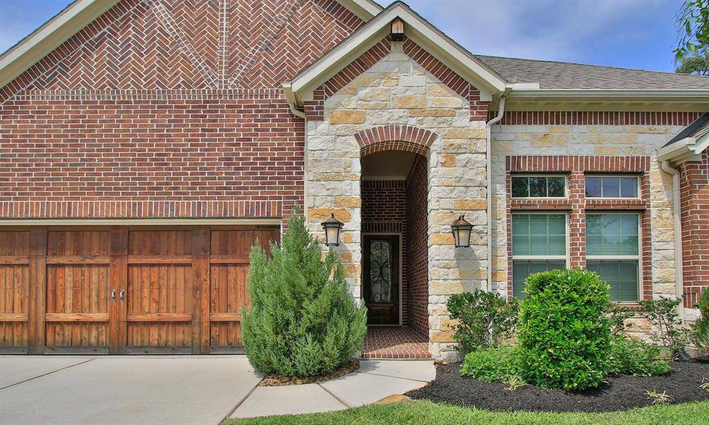 Covered front porch with stone facade, brick floors and high ceilings making it a grand entrance.