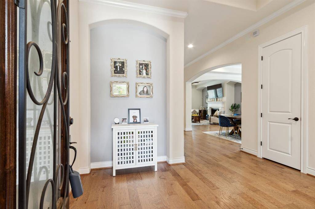 Step into a welcoming entryway featuring a stylish curved niche and convenient coat closet. Enjoy the modern sophistication of light wood floors and high ceilings throughout the home.