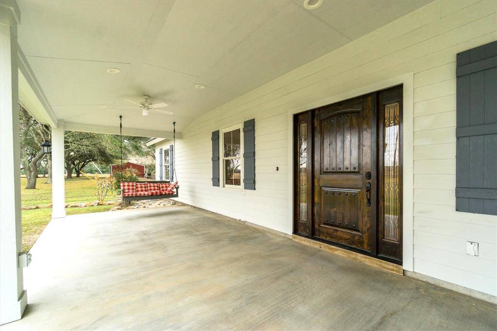 Welcome all guests through this large wooden door with side lights. Front porch swing can stay, a must for this charming farm house.
