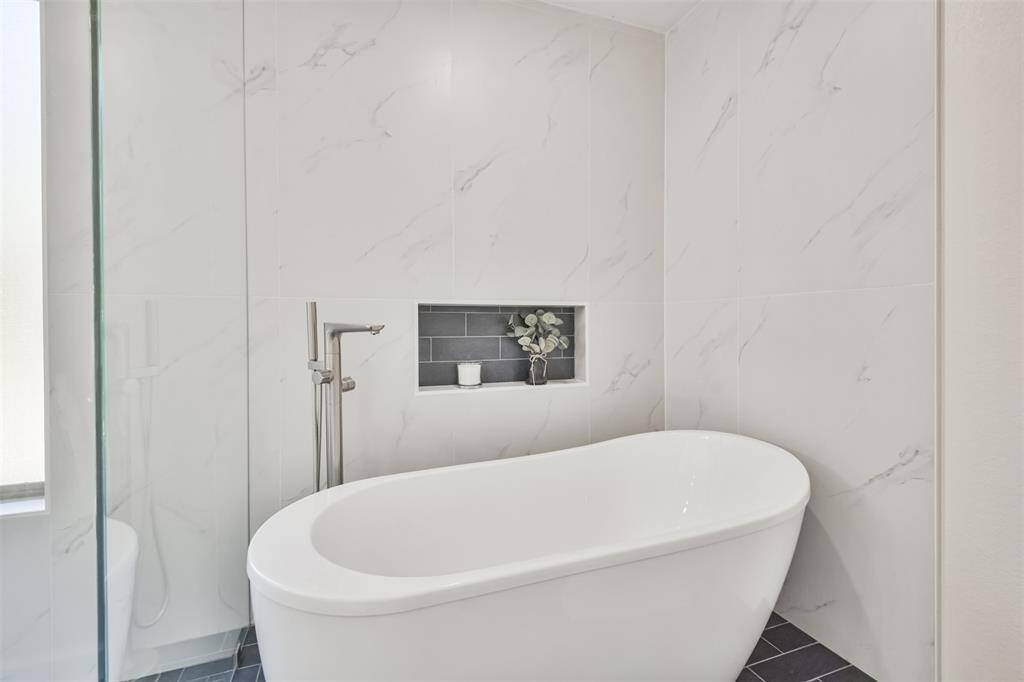 Enjoy relaxing in this lovely soaking tub with floor to ceiling stone surround and stainless fixture.