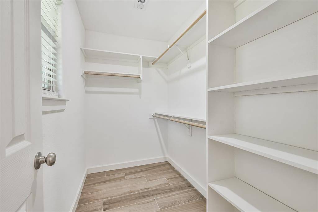 First walk in closet of primary bedroom with built in shelves.
