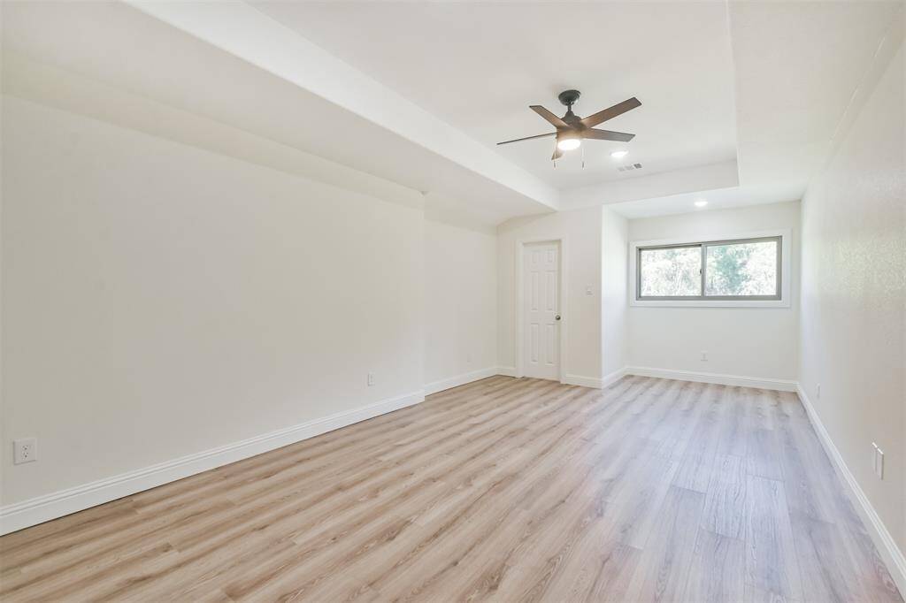 Large secondary bedroom with all new wood look flooring, vaulted ceiling and ceiling fan.