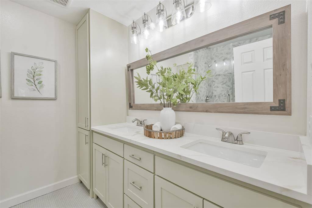 Gorgeous secondary full bath with quartz countertops, double sinks, new light fixtures, updated mirror and note the tile flooring which is spectacular!