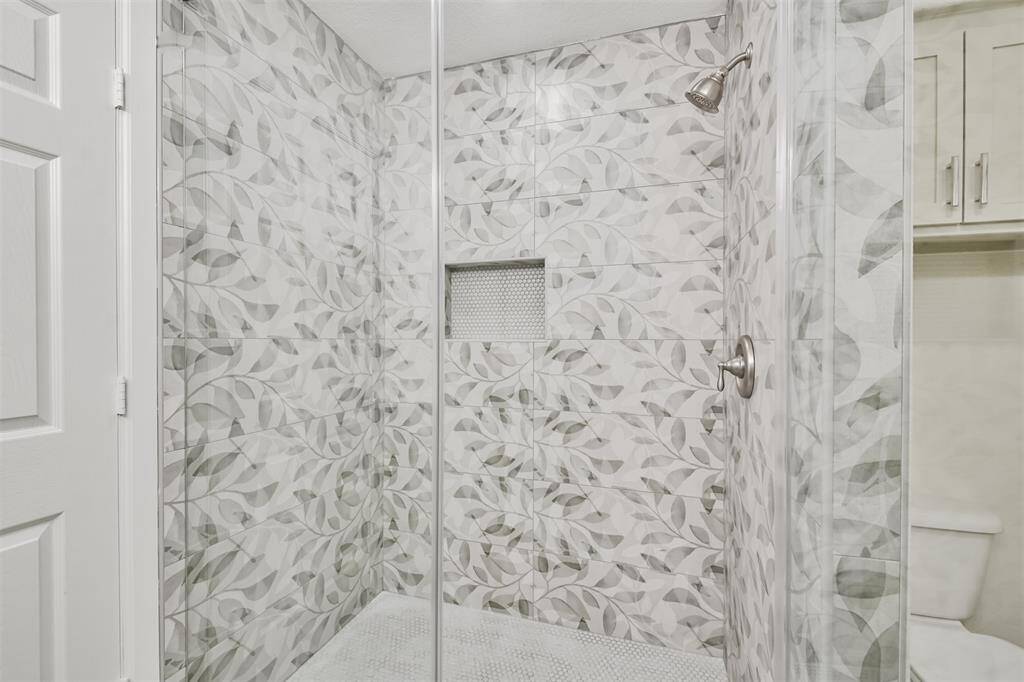 Must see step in shower with beautiful muted leaf pattern tile, frameless glass and stainless fixtures.