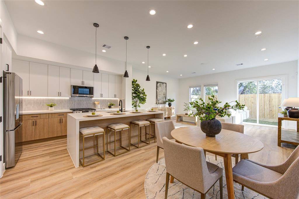 Chef's kitchen with designer tile selections, white quartz counters with 2" thick waterfall island, soft close European style white oak and white slim shaker cabinetry, stainless steel smart appliances, large built-in pantry, and tons of natural light.