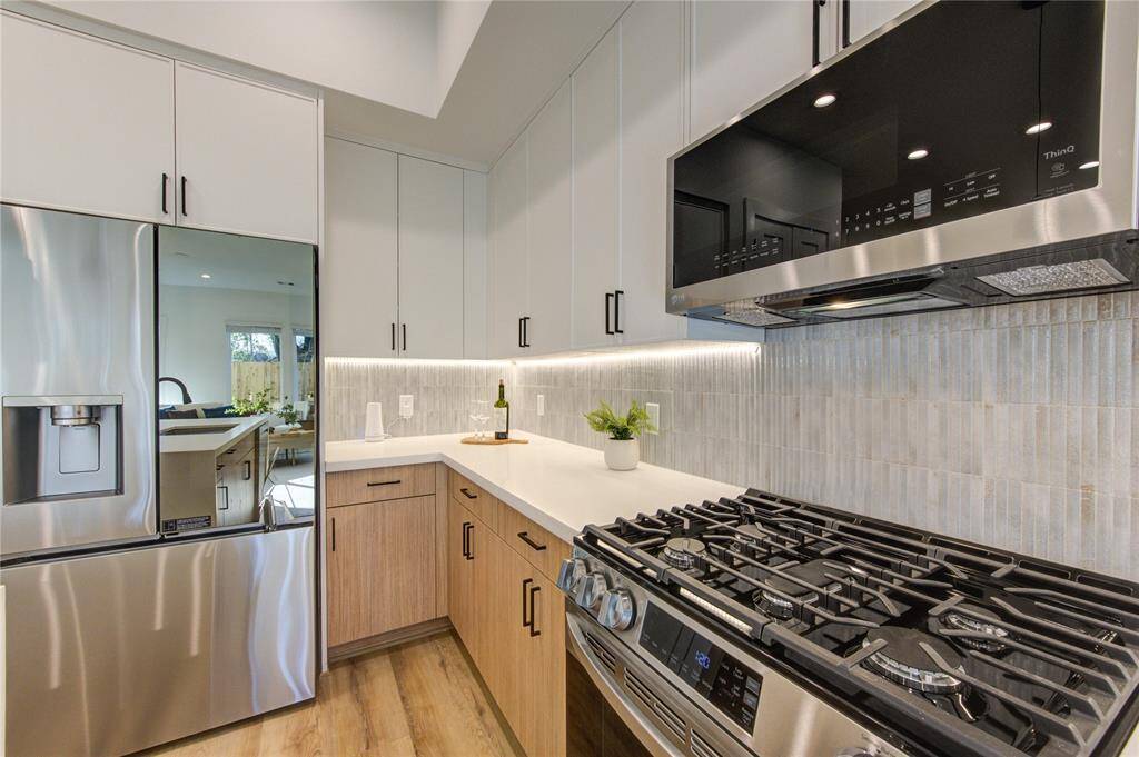 Chef's kitchen with designer tile selections, white quartz counters with 2" thick waterfall island, soft close European style white oak and white slim shaker cabinetry, stainless steel smart appliances, and tons of natural light.