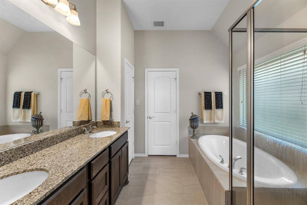 Primary bathroom with dual vanities, separate shower, soaking tub, and walk-in closet.