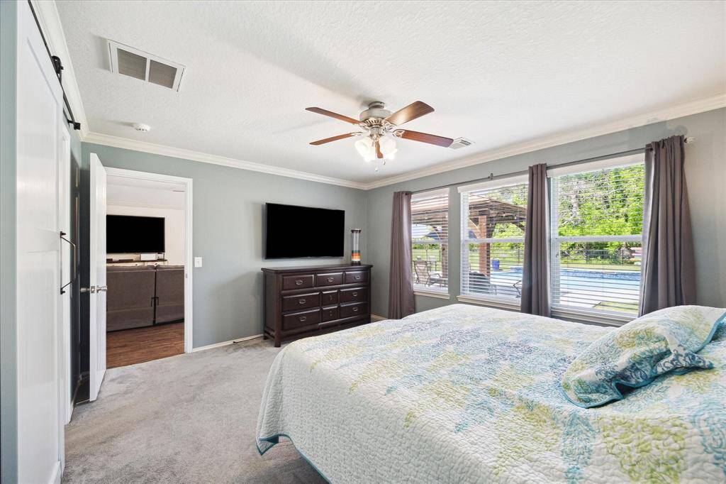 Large primary bedroom with picture windows overlooking pool and backyard.