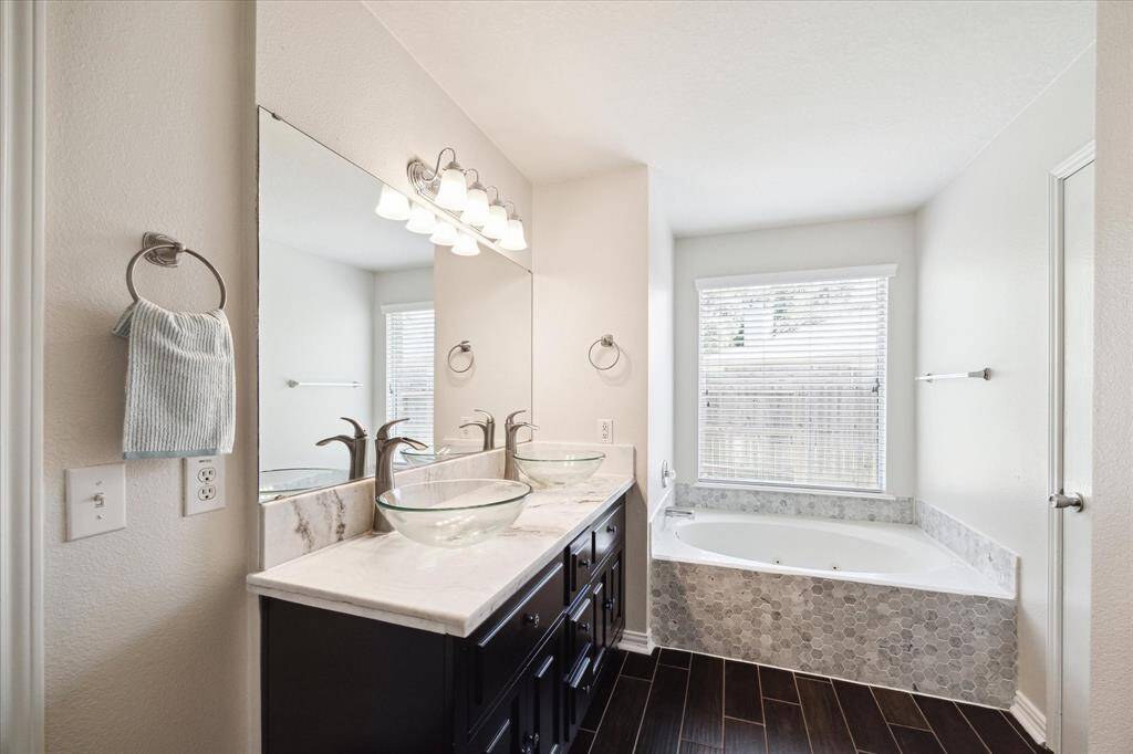 Primary bathroom with separate shower and soaking tub. Double raised sinks.