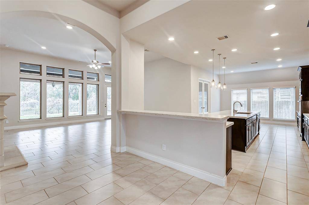 Connecting the formal dining room to the stunning kitchen is a spacious raised breakfast bar, providing ample room for casual dining or quick meals. This open, functional space offers the perfect spot for morning coffee, a casual bite, or a place for guests to gather while meals are being prepared.