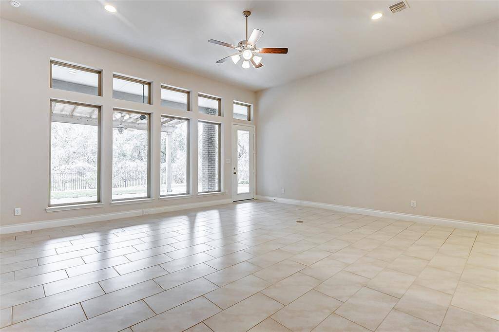 The oversized family room offers a stunning view of the expansive covered patio and lush backyard, creating a perfect indoor-outdoor connection. With high ceilings, recessed lighting, and elegant tile flooring, the space exudes both style and comfort.