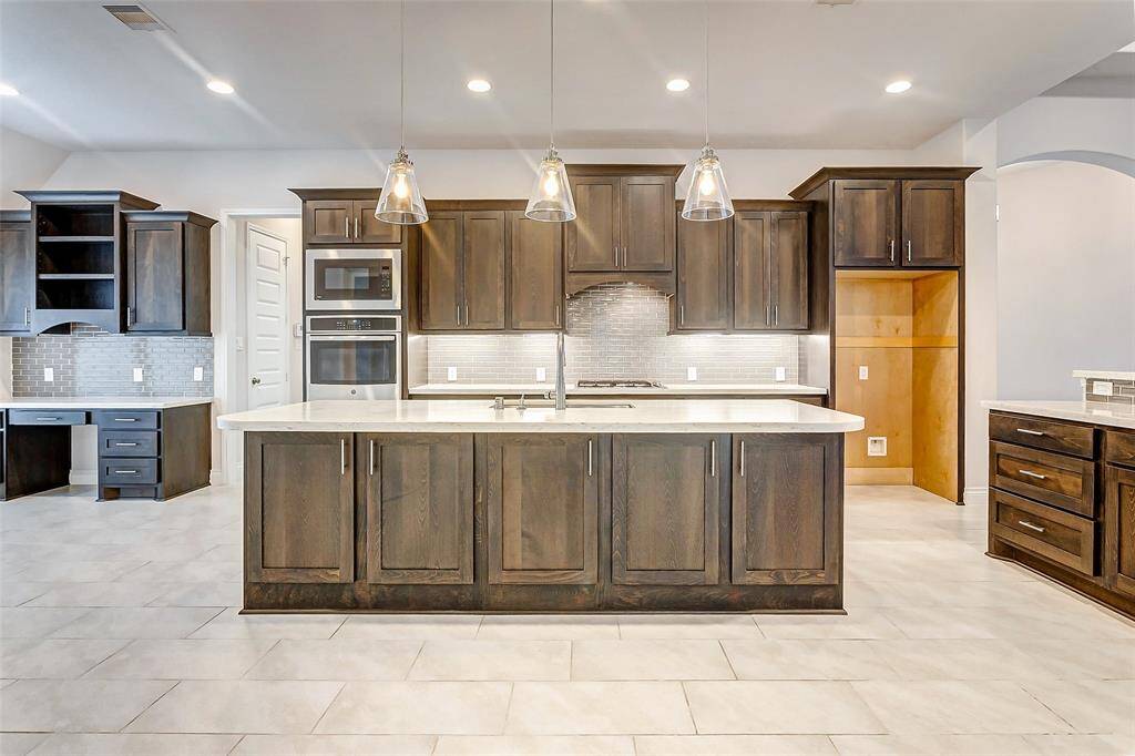 The heart of this home is the chef’s kitchen—a true culinary masterpiece that seamlessly combines beauty and functionality. At its center, a generously sized island offers abundant storage on both sides, complemented by elegant pendant lighting overhead, creating a striking focal point in the space.