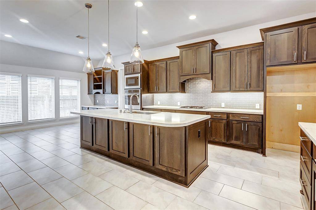 The kitchen features breathtaking quartz countertops that add a touch of sophistication, complemented by a beautifully designed backsplash that enhances the overall aesthetic. The 42-inch upper cabinetry offers ample storage space, while under-cabinet lighting casts a warm, inviting glow, highlighting the exquisite details.