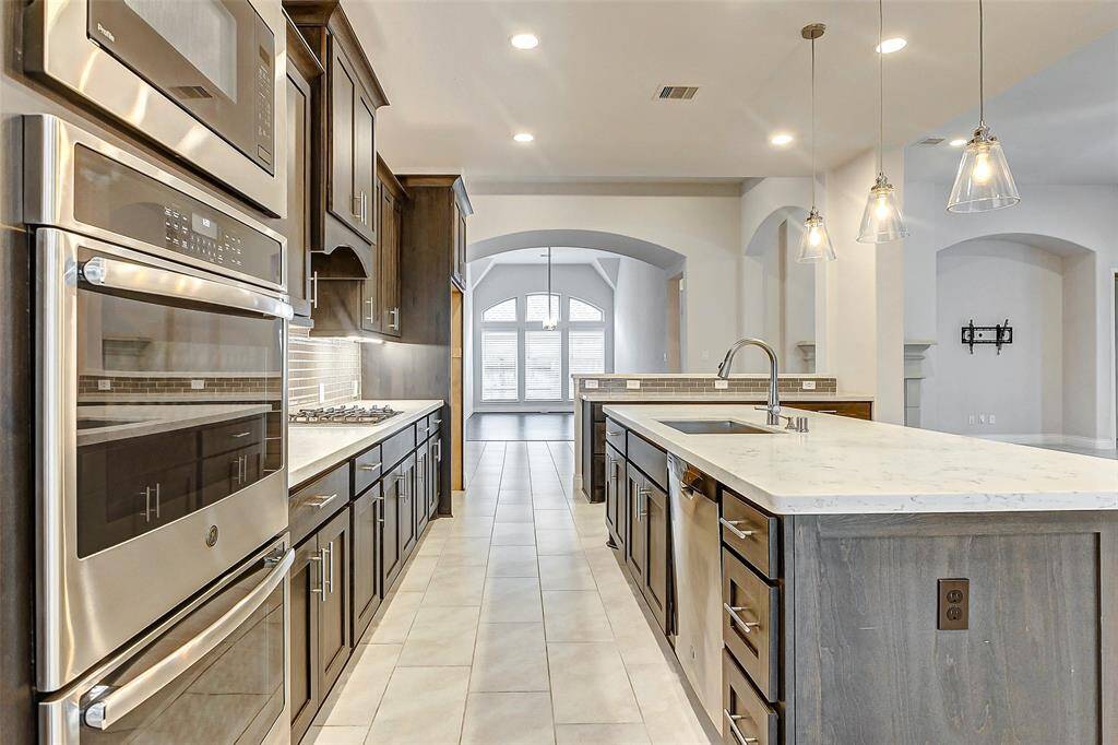 High-end stainless steel appliances—including double ovens, a built-in microwave, dishwasher, and cooktop—elevate the space, while ample storage throughout ensures everything has its place.