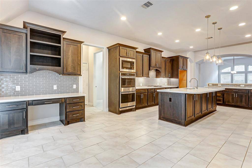 The adjoining breakfast area features a thoughtfully designed built-in desk. Whether you're managing the family calendar, paying bills, or handling other household duties, this dedicated workspace ensures everything is neatly organized and easily accessible.