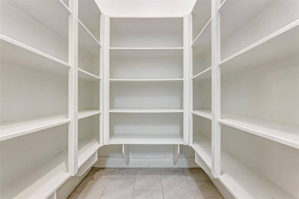 An oversized walk-in pantry, equipped with extensive shelving, provides maximum storage for all your kitchen essentials, ensuring everything is easily accessible.
