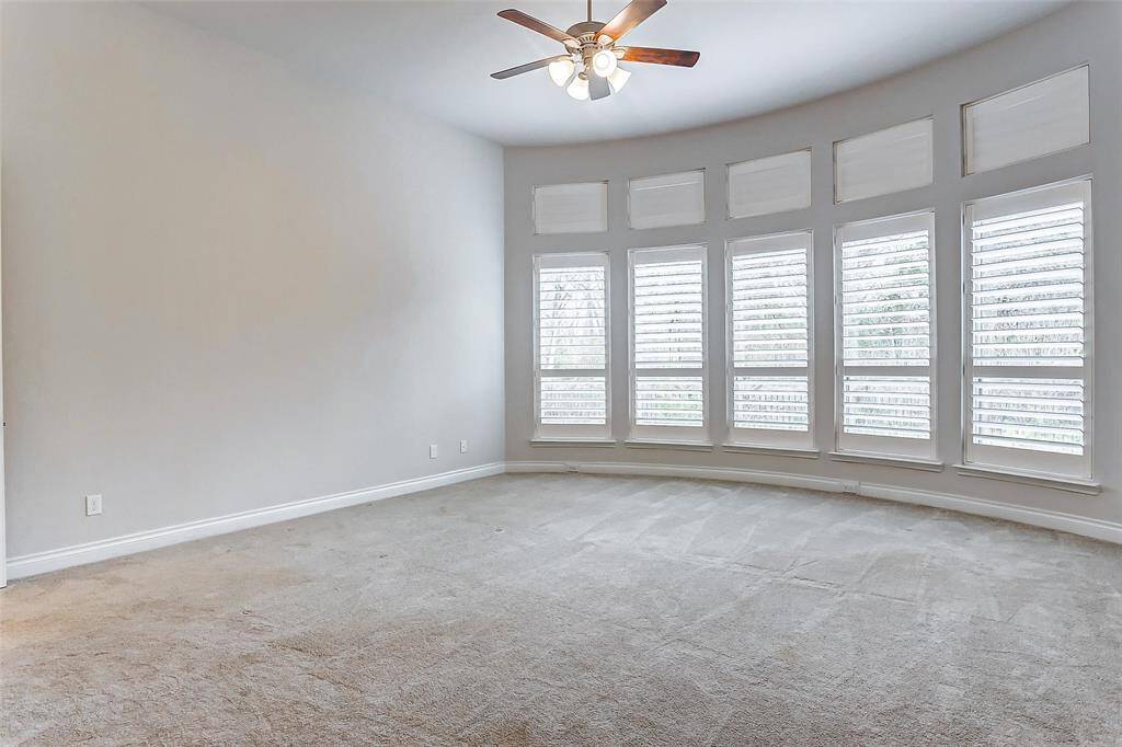 Step into the luxurious primary suite, a true retreat designed for relaxation and comfort. A striking curved wall of windows with elegant plantation shutters floods the room with an abundance of natural light. The soaring 12-foot ceiling adds a sense of grandeur, elevating the space and enhancing its open, airy feel.