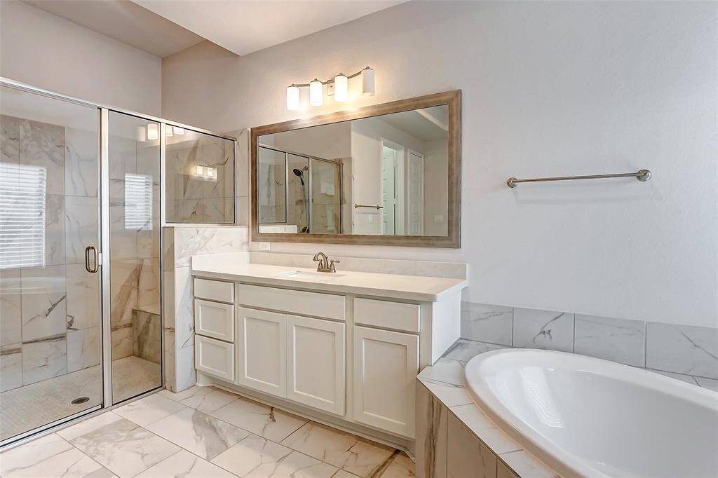 The second vanity provides additional space for your bathroom essentials, helping you stay organized while maintaining a clean, uncluttered look. The large framed mirror and overhead vanity lighting add a final touch of sophistication to the space.