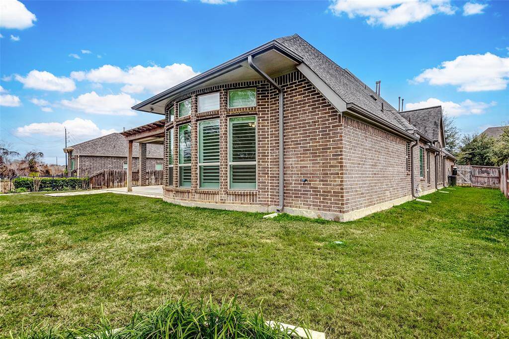 From the corner of the yard, the view beautifully showcases the home's pristine brick exterior, adding to its timeless charm and curb appeal. The rich, textured brickwork complements the lush landscaping, creating a stunning contrast that highlights the home's architectural elegance.