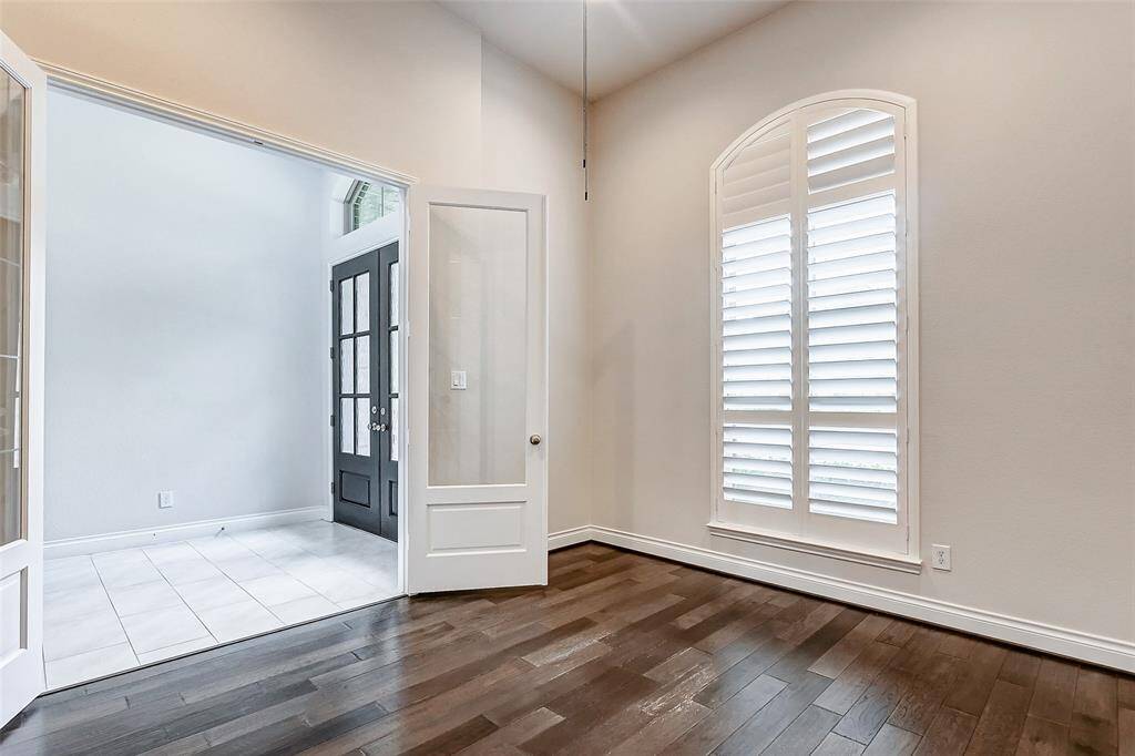 The private home office boasts gleaming hardwood floors, a soaring ceiling with a fan, and a large window adorned with plantation shutters. Its stylish design and functional layout make it an ideal space for both work and personal projects, offering a serene and productive environment for all your needs.