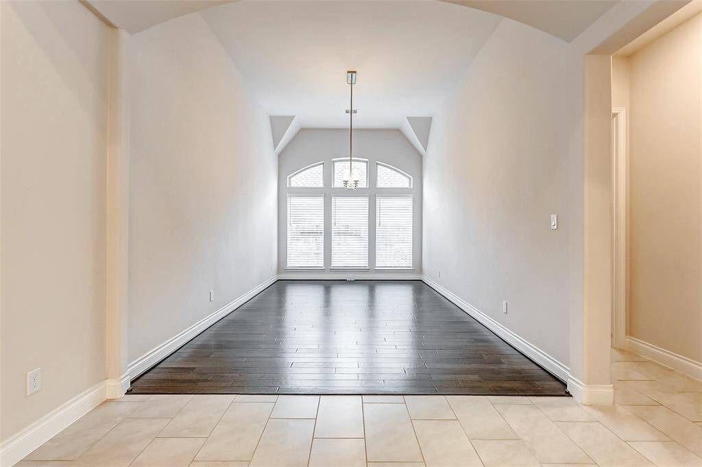 The elegant formal dining room features gleaming hardwood floors that add warmth & sophistication to the space. A soaring ceiling, enhanced by a stunning chandelier, creates a grand & inviting atmosphere, while a wall of windows floods the room with abundant natural light, further elevating the ambiance.