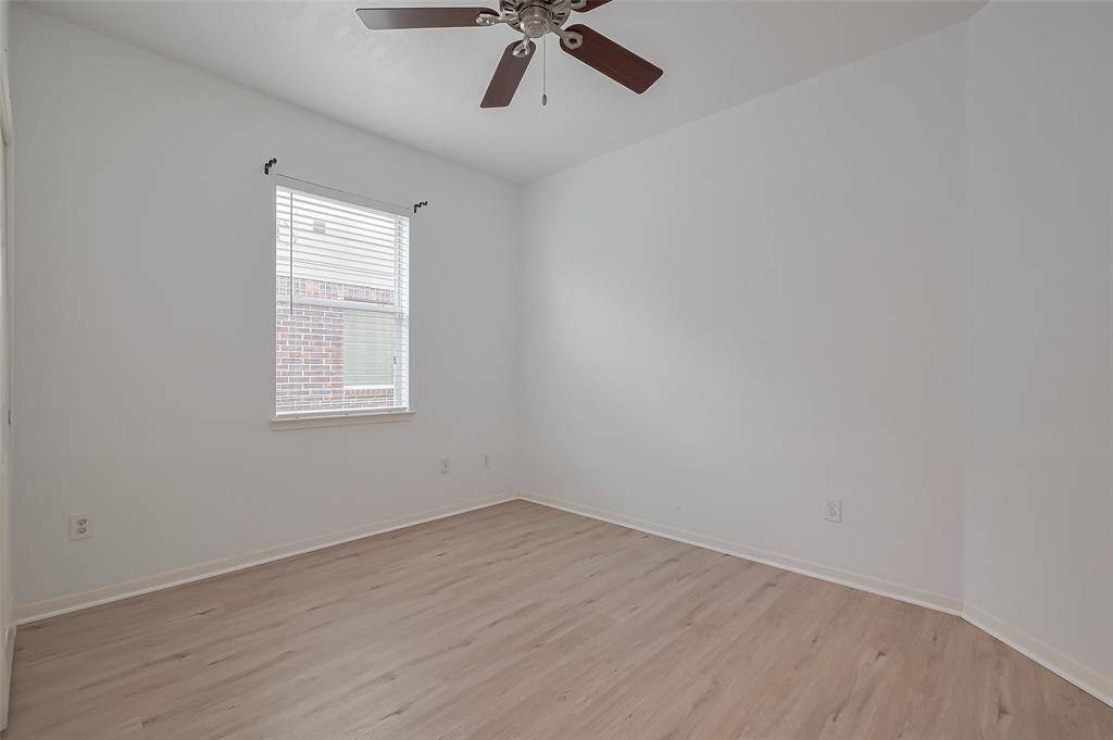 Another comfortable bedroom with a ceiling fan and window, offering flexibility for guests, hobbies, or a work-from-home setup.