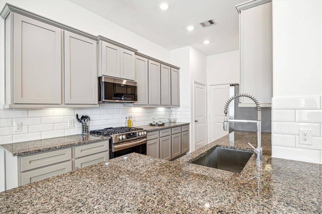 Kitchen includes stainless steel appliances, two pantries, and door access to the attached 2-car garage. Refrigerator is included in the sale.