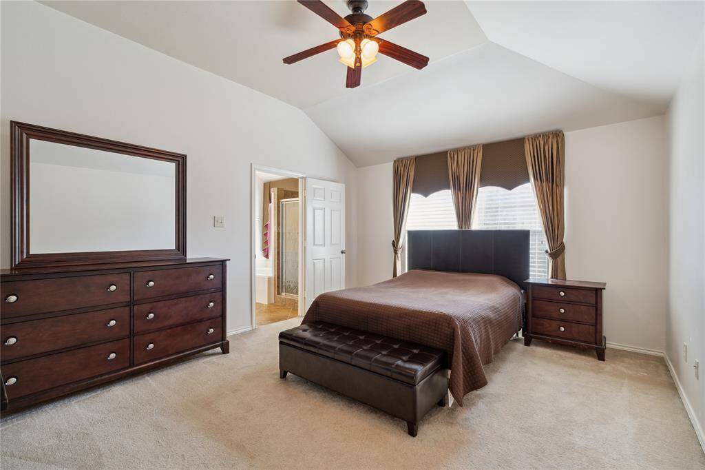 The primary bedroom offers a relaxing retreat with vaulted ceilings and plush carpeting, creating a cozy yet spacious atmosphere.